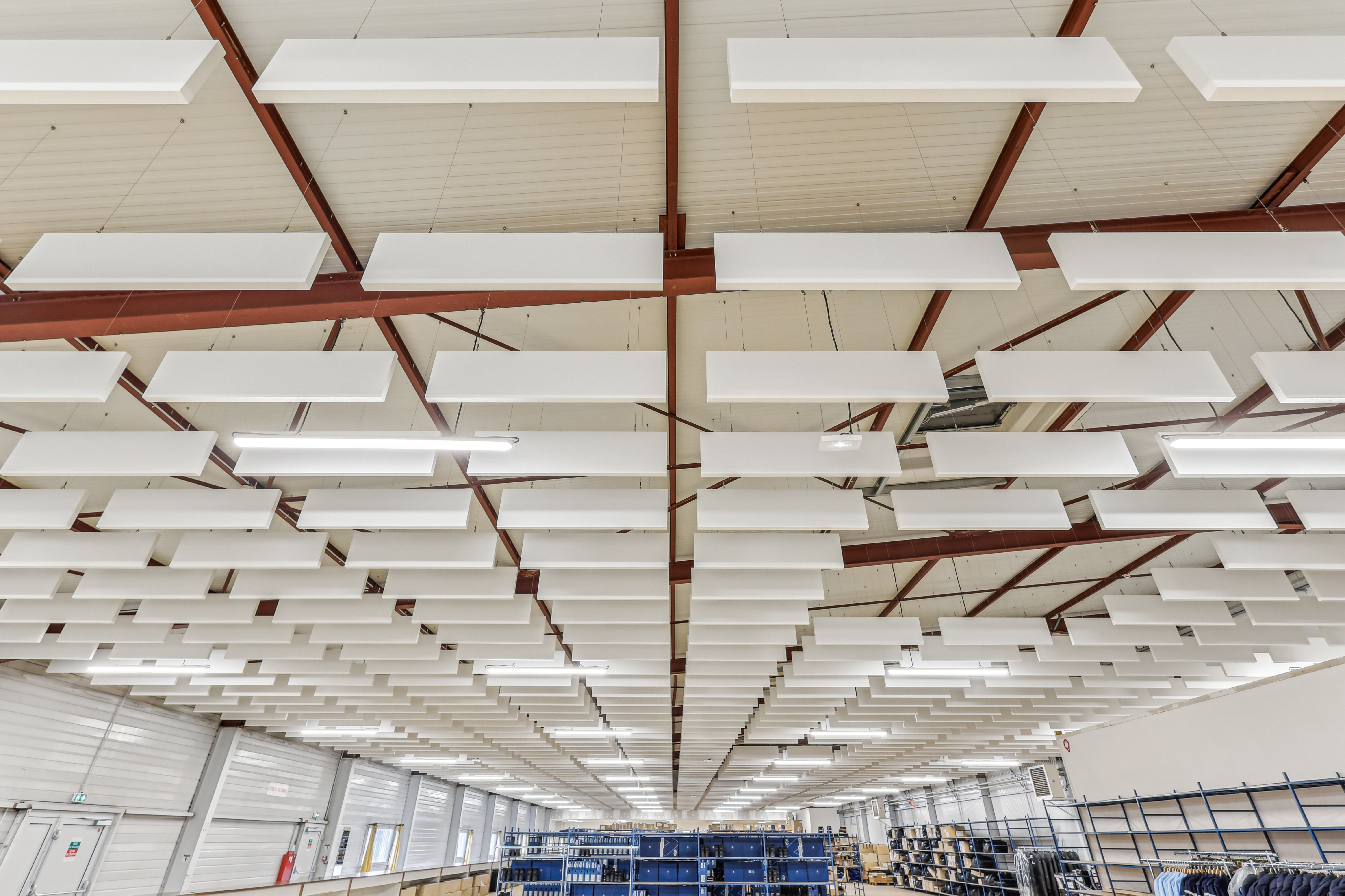 Photo en vue plongeante de nombreuses baffles acoustiques suspendues au plafond organisées en plusieurs rangées.