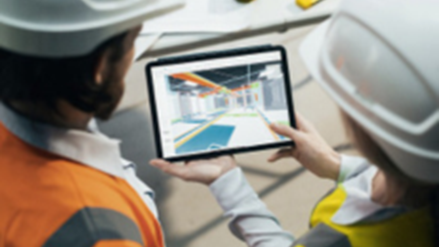 Deux professionnels du bâtiment, équipés de casques et gilets de sécurité, consultent une maquette numérique de chantier sur une tablette. La scène se déroule dans un environnement de bureau ou de zone technique avec des outils de mesure posés sur la table.