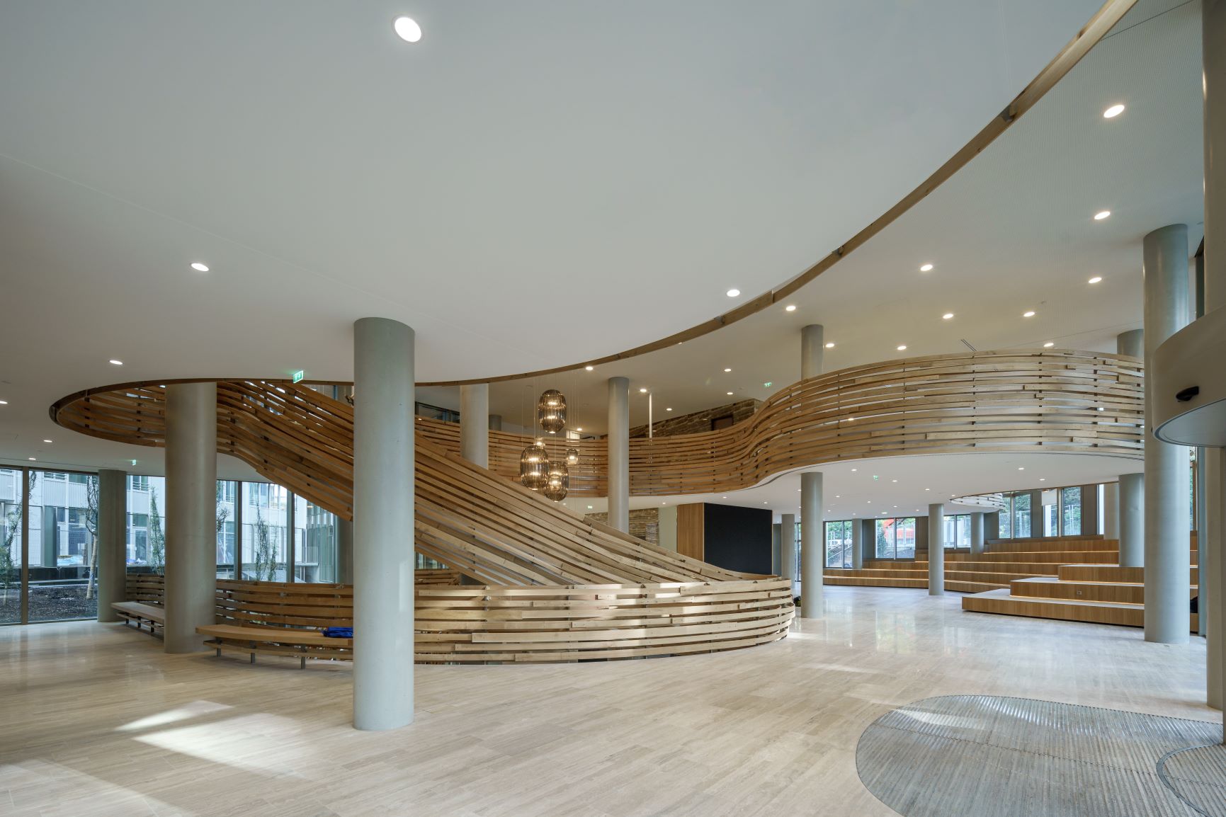 Hall d'entrée du bâtiment avec un large escalier et des solution de toile technique au plafond.