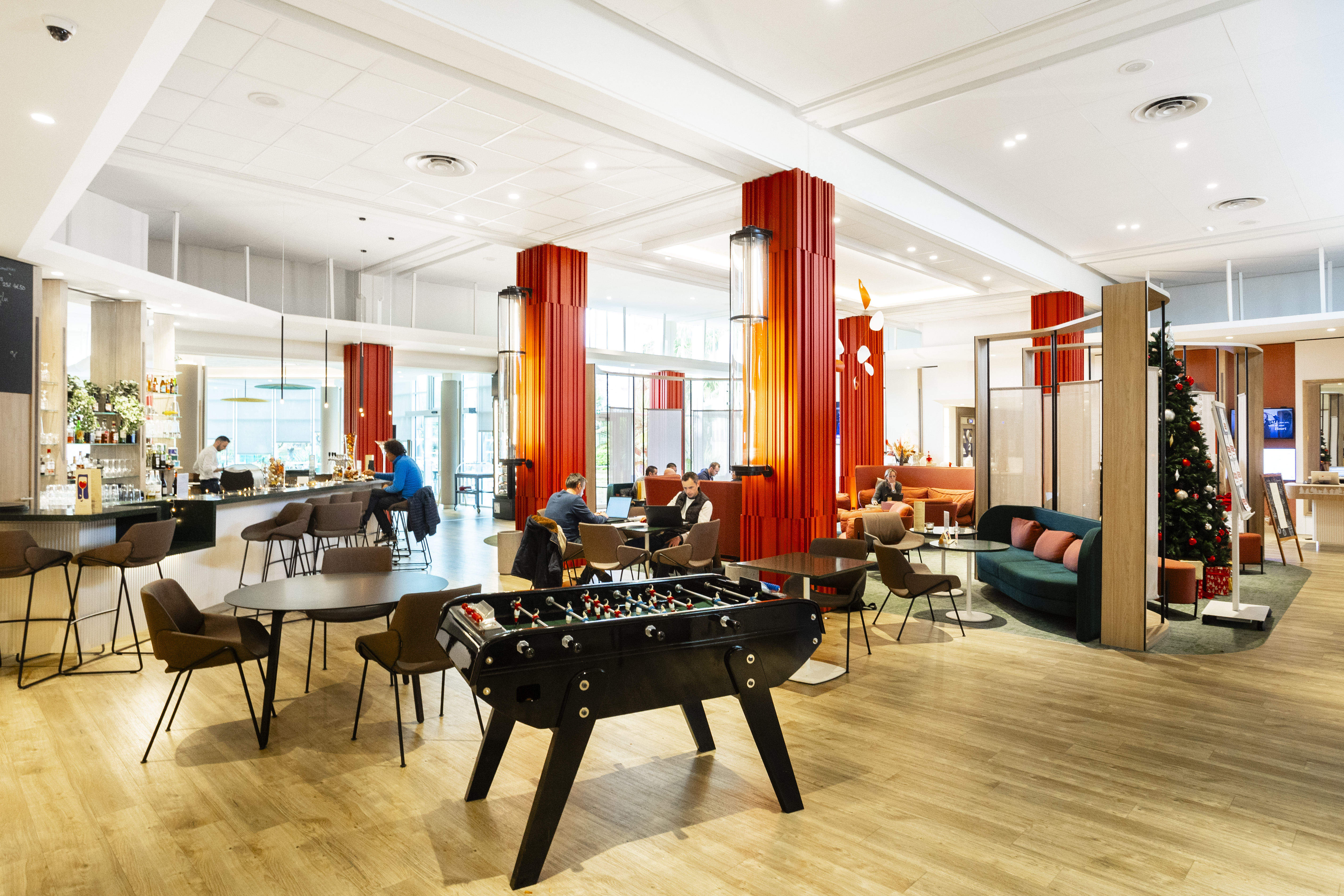Photo hall d'hôtel avec babyfoot au centre et solutions de toile acoustique blanche au plafond.