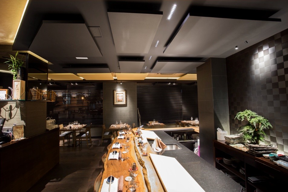 Restaurant au style chaleureux mêlant bois massif, éclairage doux et comptoir ouvert sur la salle.