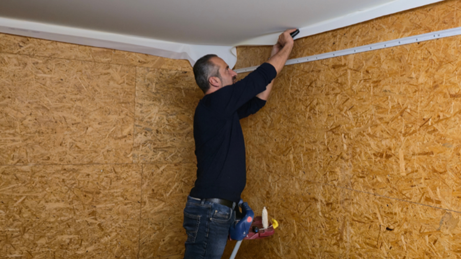 Un poseur est en train de poser une toile tendue blanche au plafond