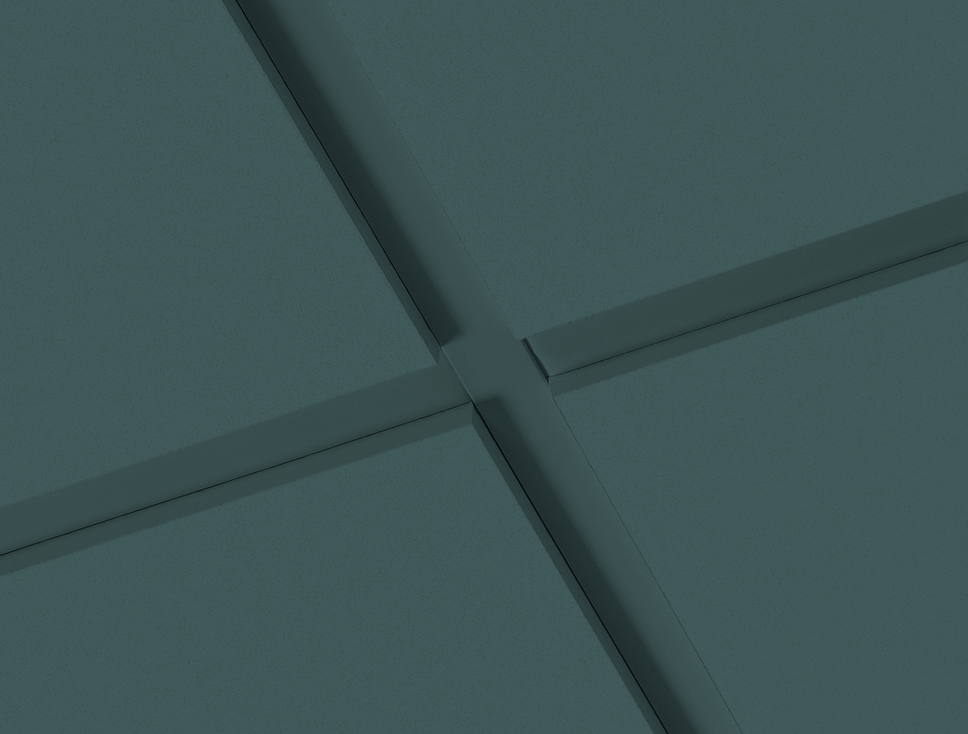 Close-up view of intersecting acoustic ceiling panels in a dark green colour.