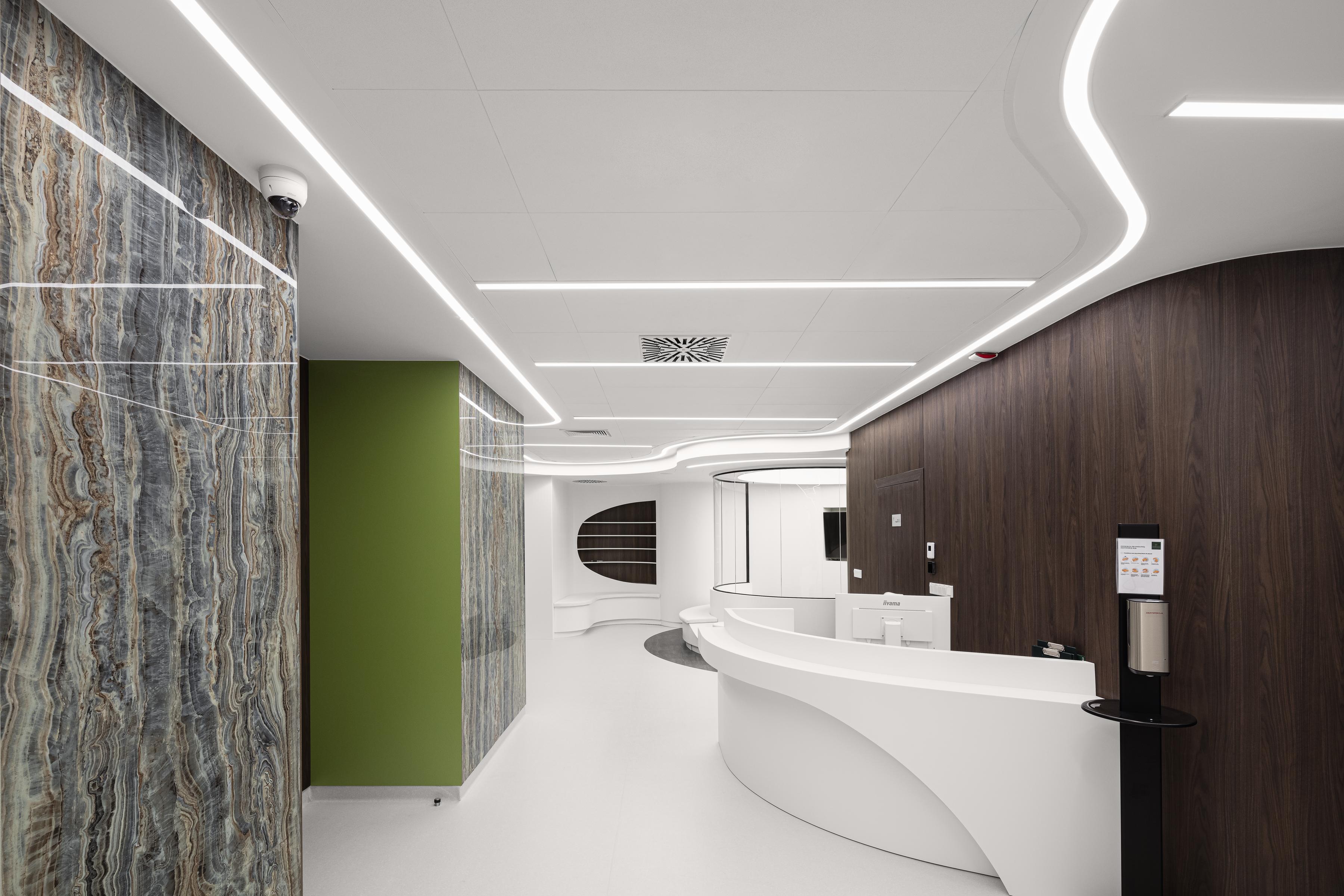 Hospital reception area with suspended acoustic ceiling, dark brown interior details and walls with artistic motif