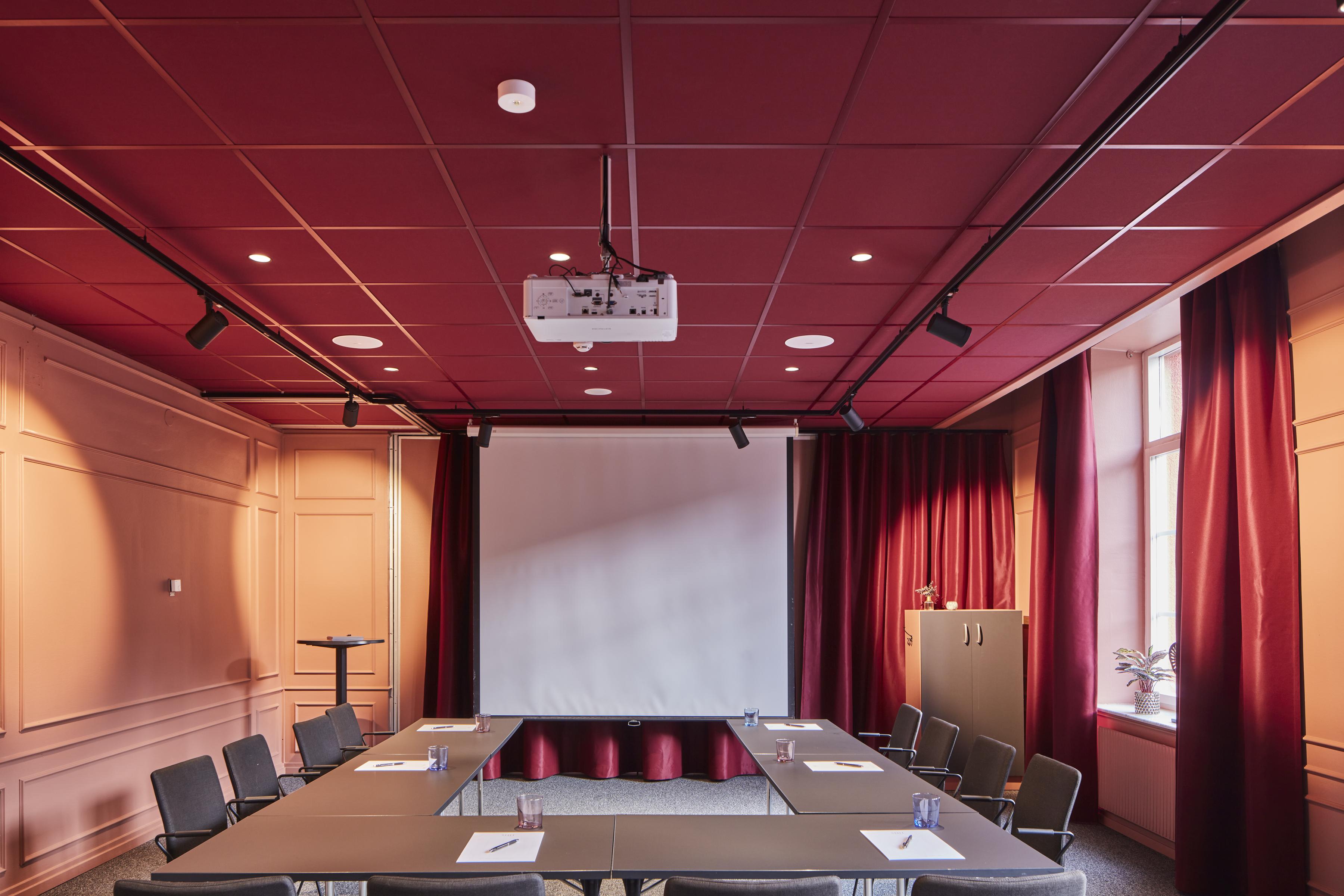 Conference room with dark red suspended acoustic ceiling with matching grids