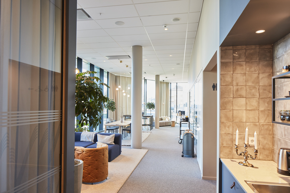 White, suspended acoustic ceiling in office social area with furniture in soft colours