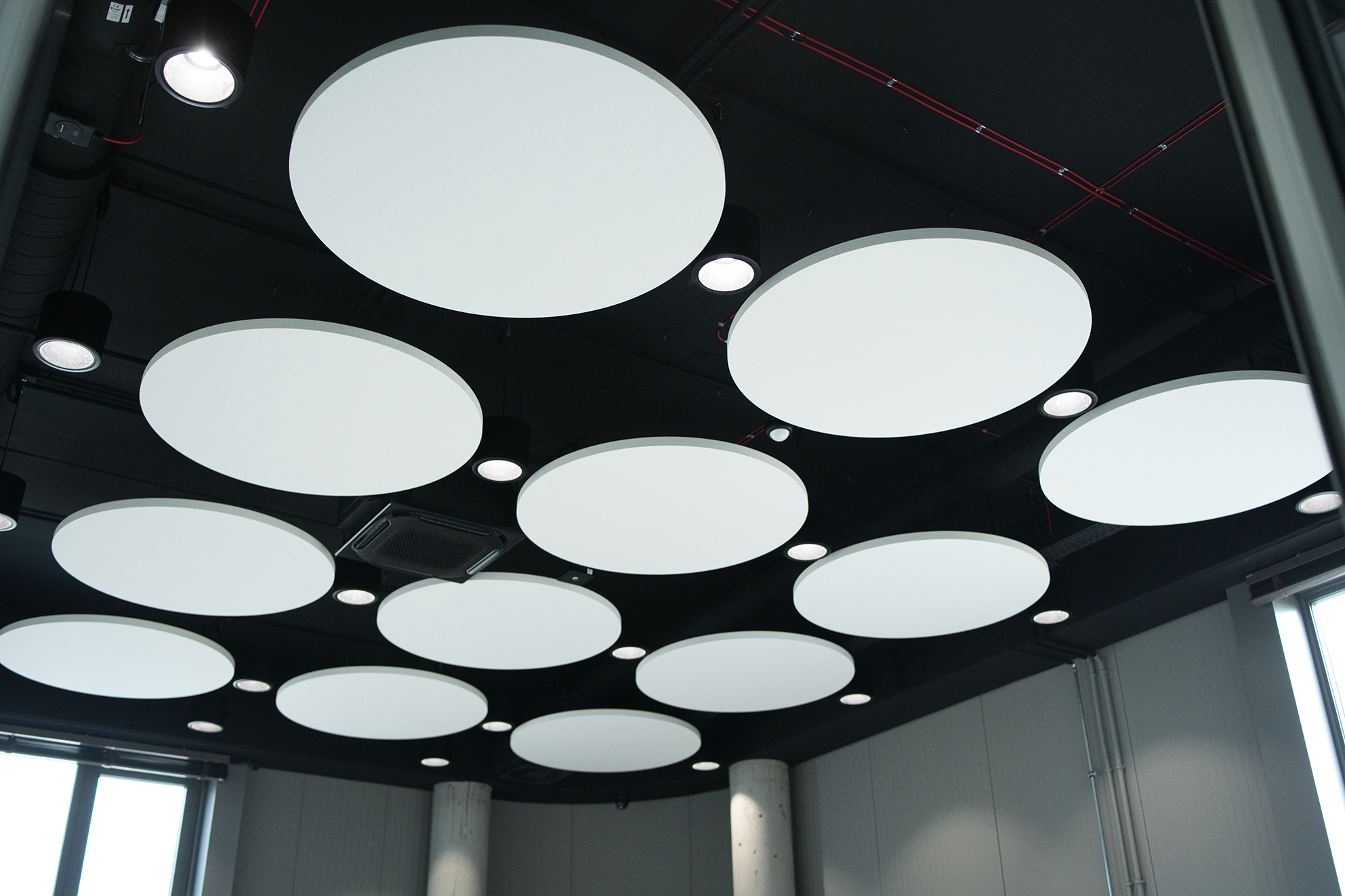 Circular acoustic ceiling units installed in a suspended layout across an open interior space
