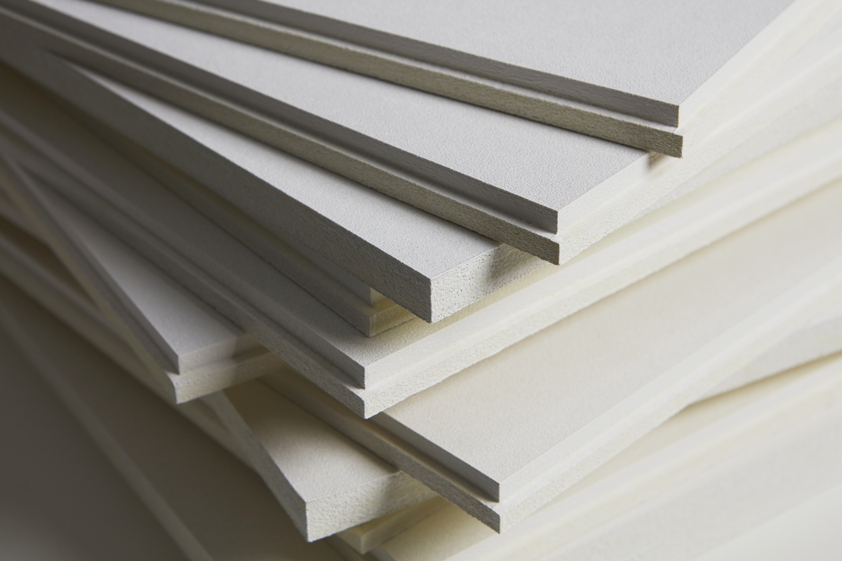 A close-up view of a stack of rectangular, white acoustic panels with smooth edges. The panels are arranged in a slightly staggered manner, displaying the thickness and texture of the material. The background is blurred.
